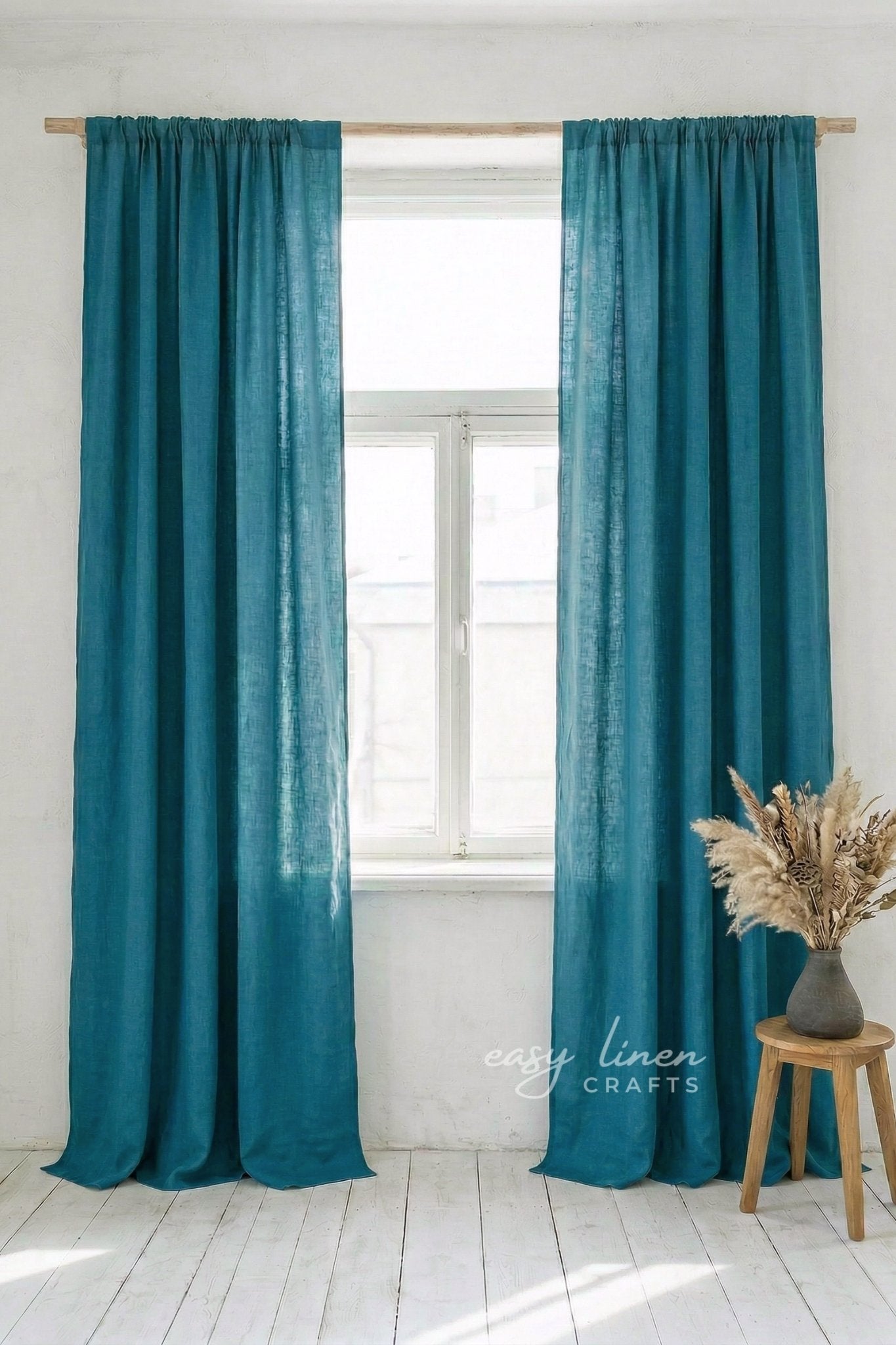 Teal curtains hanging in a window with a white background