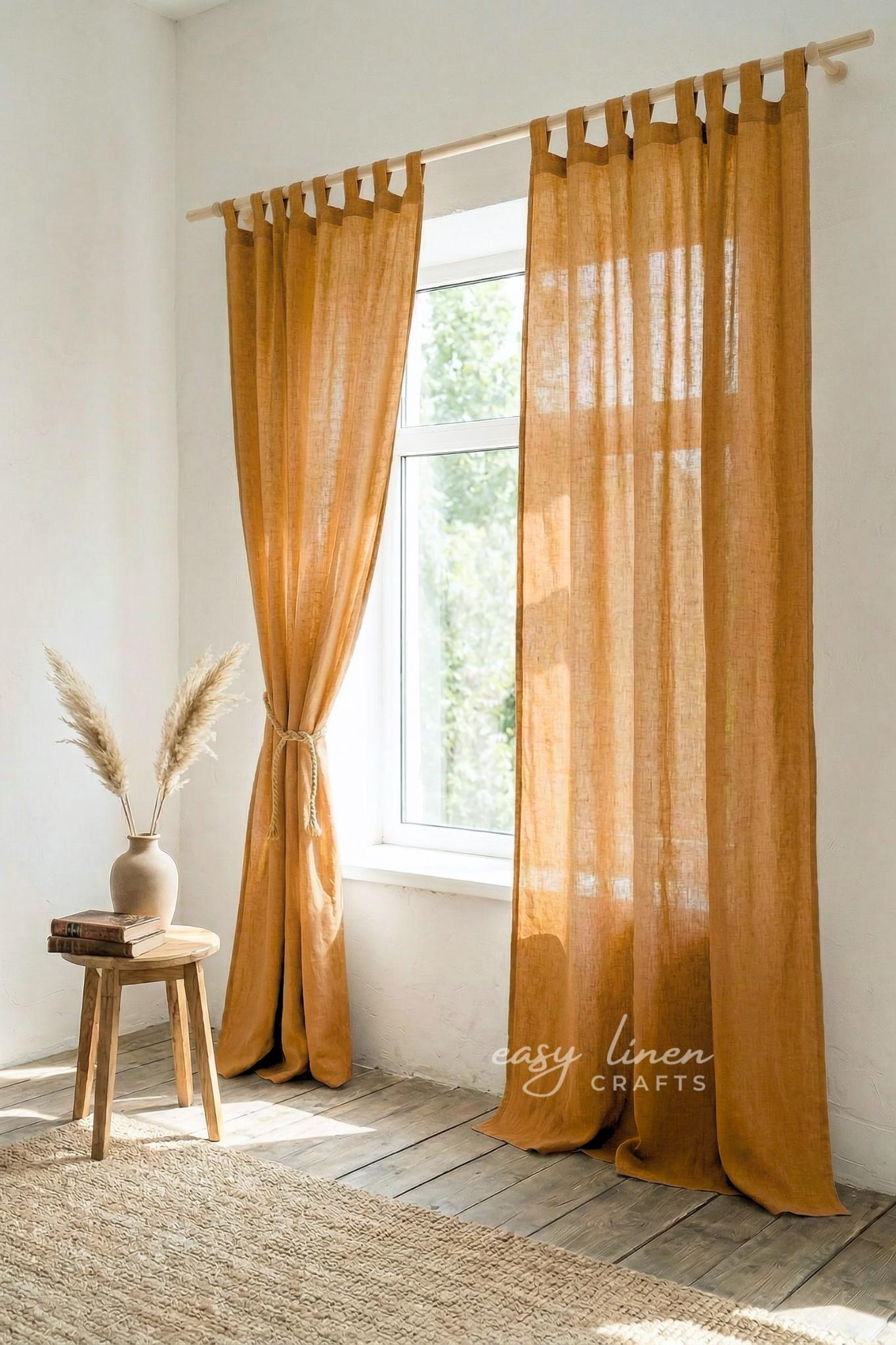 Mustard yellow curtains hanging in a room with a wooden stool and vase.