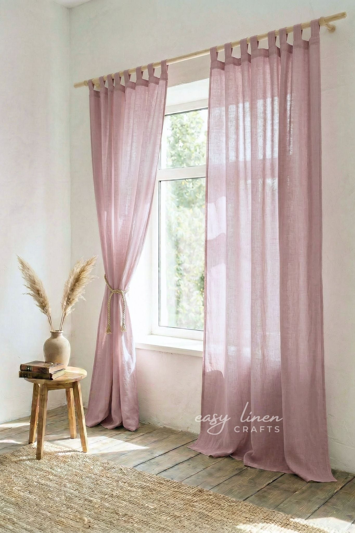 Pink curtains hanging in a room with a wooden stool and vase.