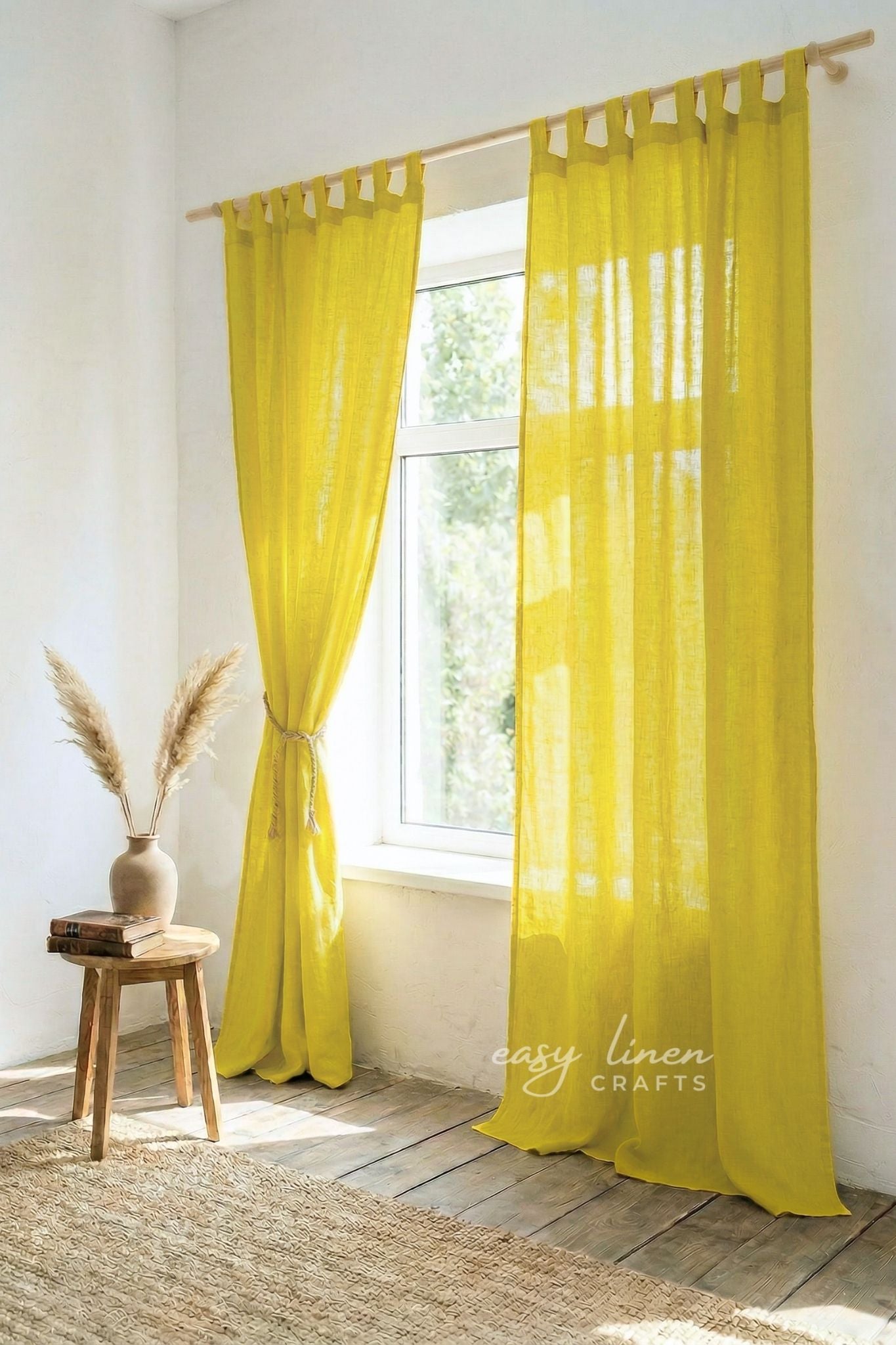 Yellow curtains hanging in a room with a wooden stool and vase.