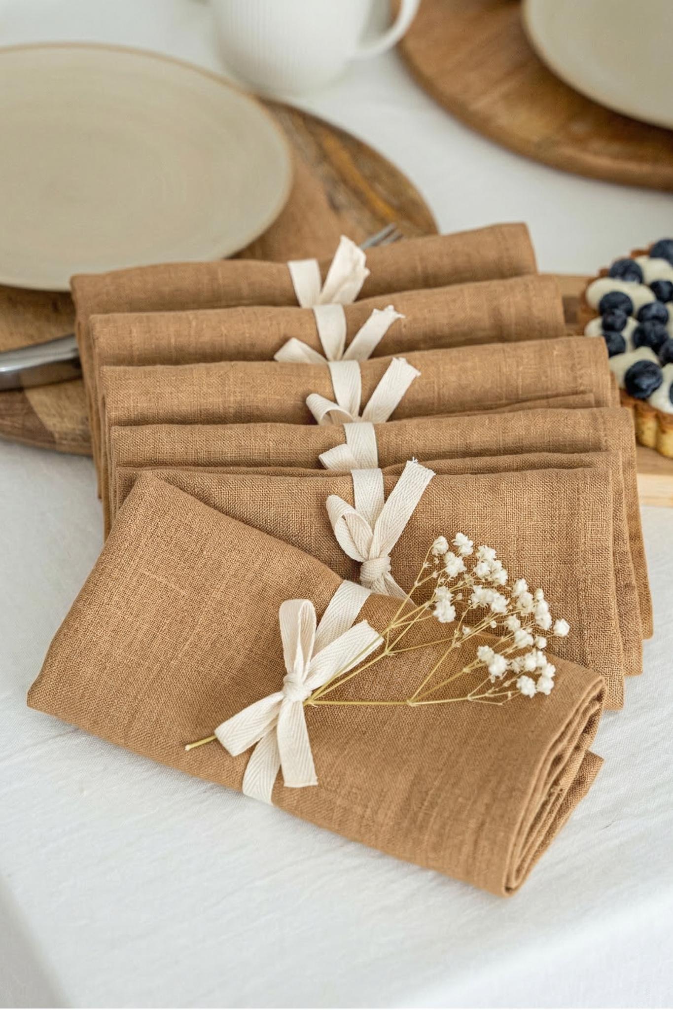 Set of brown napkins with white ribbons on a table setting.