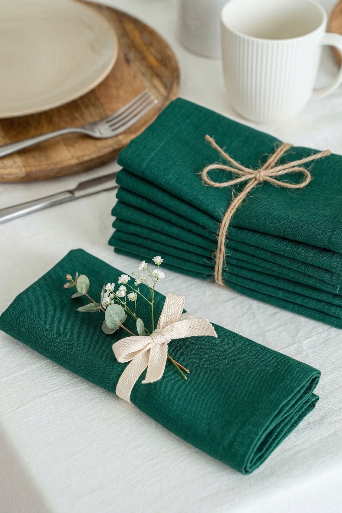 Set of green napkins with a decorative bow and small plant on a white surface