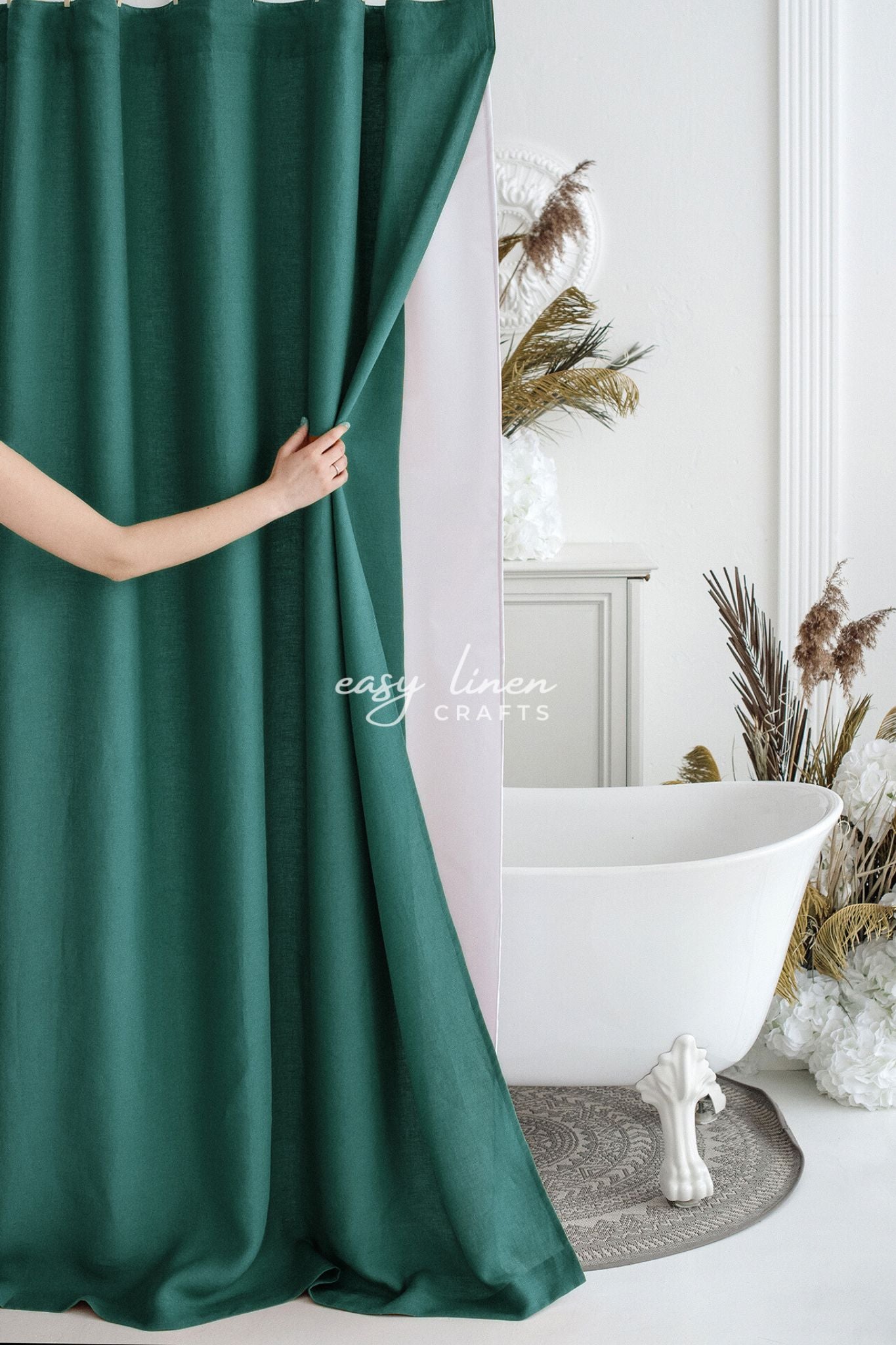Person holding a green shower curtain in a bathroom with a white bathtub and decorative elements.