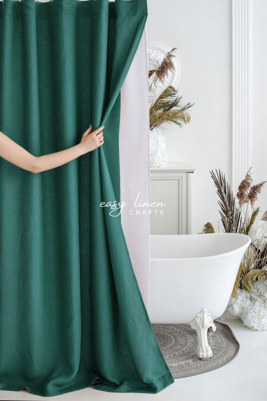 Person holding a green shower curtain in a bathroom with a white bathtub and decorative elements.