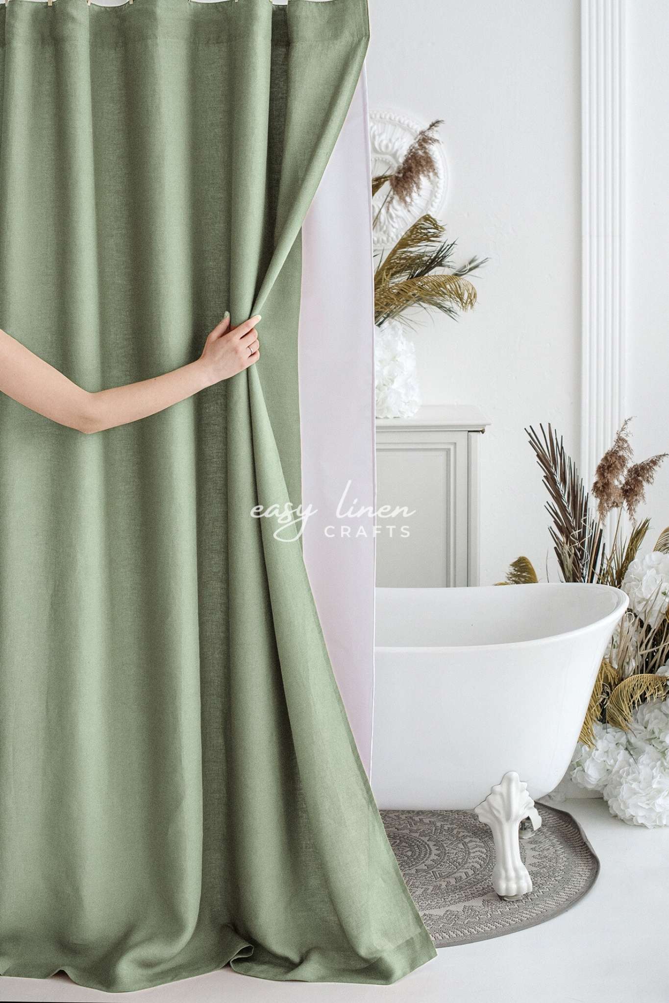 Person holding a green shower curtain in a bathroom with a white bathtub and decorative elements.