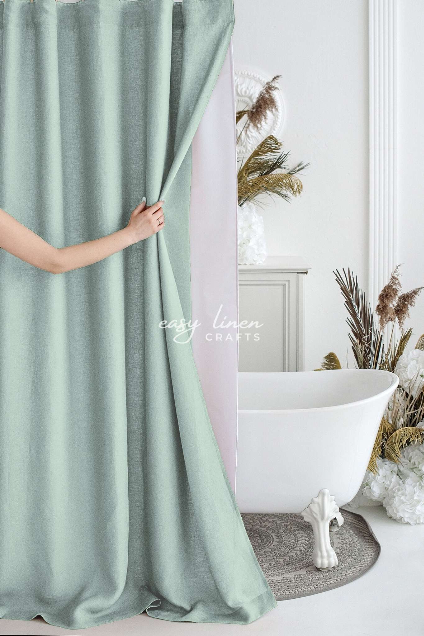 Person holding a mint green curtain in a bathroom with a white bathtub and decorative elements.