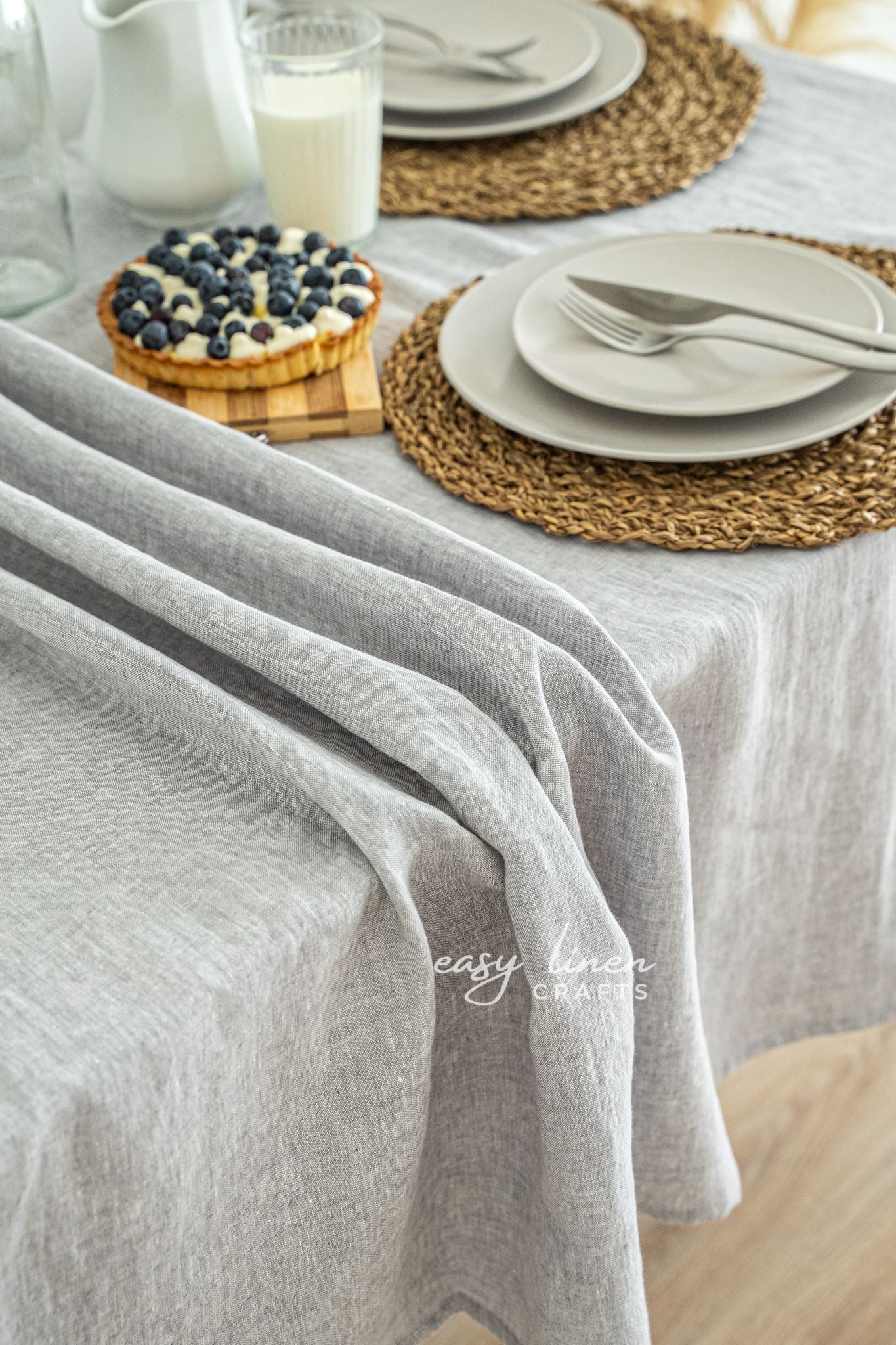 Table setting with a gray tablecloth, plates, and a small dessert on a white surface.
