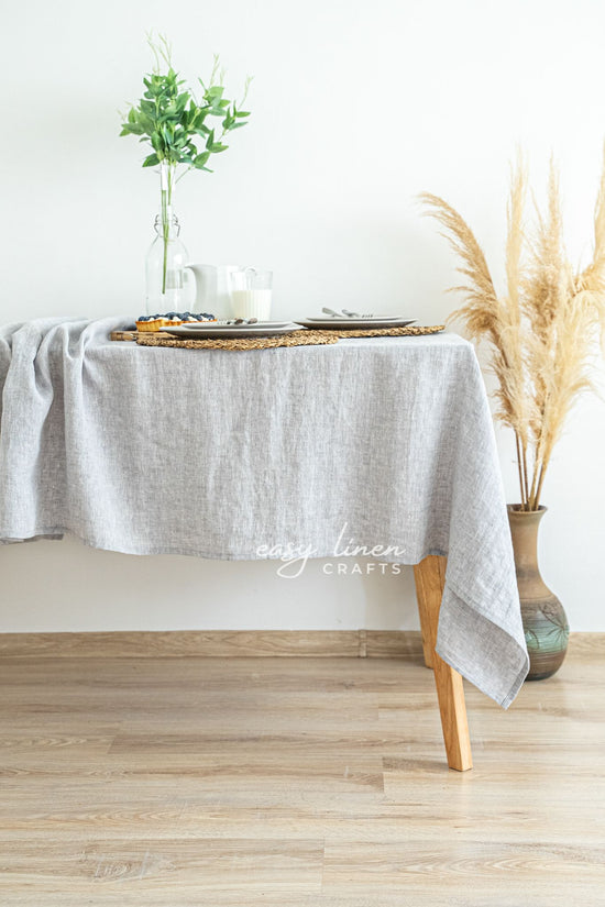 Gray linen tablecloth on a wooden table with decorative elements in a minimalistic setting.