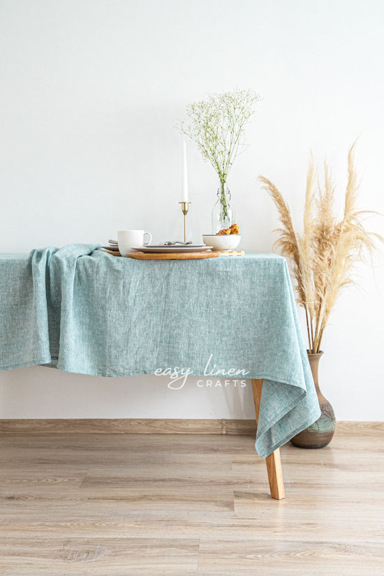 Green linen tablecloth on a wooden table with decorative elements.