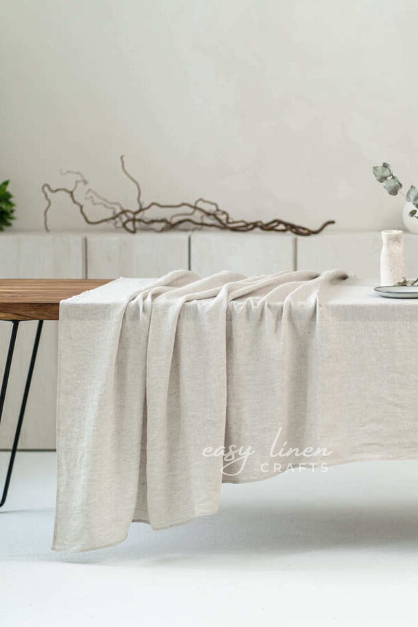 Beige linen tablecloth draped over a wooden table with a minimalistic background.