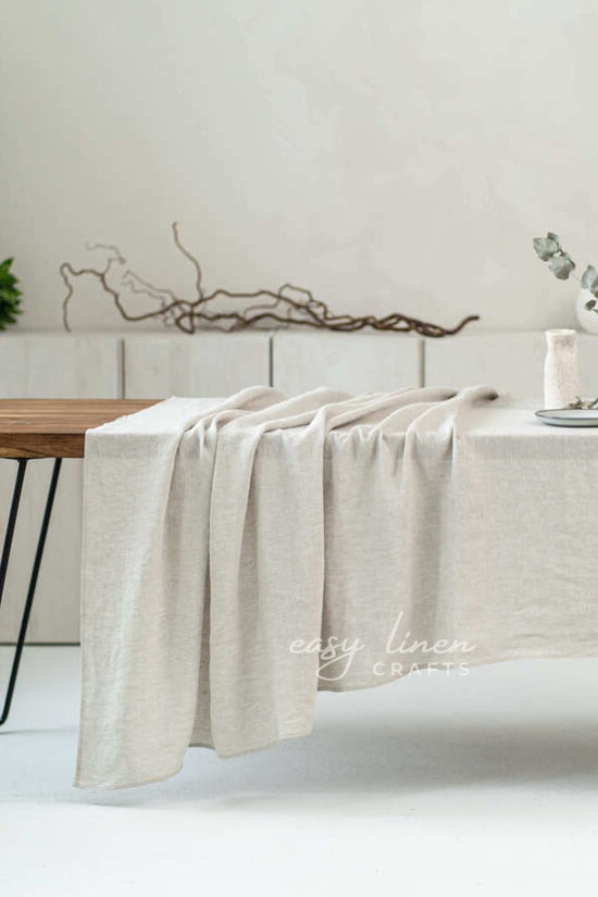 Beige linen tablecloth draped over a wooden table with a minimalistic background.