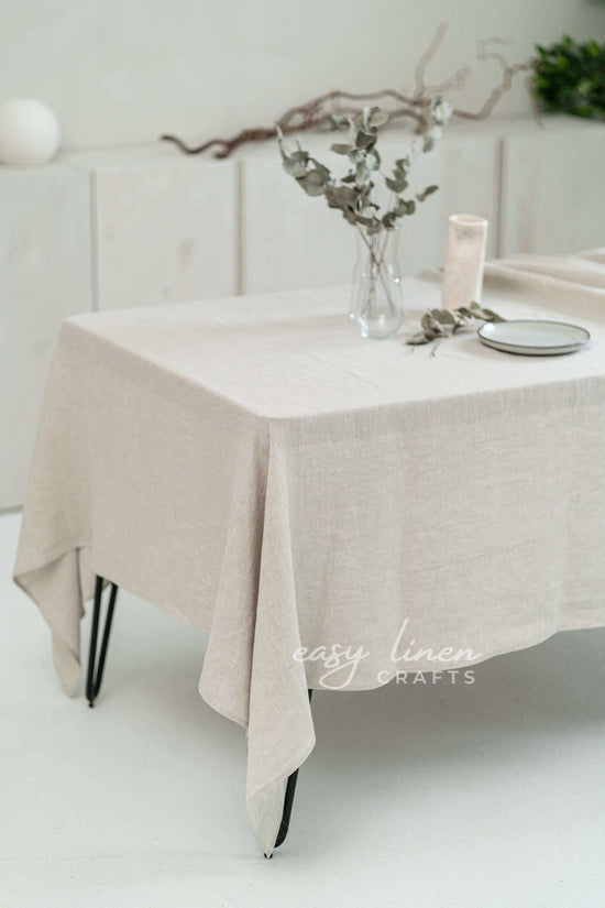Beige linen tablecloth on a table with decorative elements in a minimalistic setting.