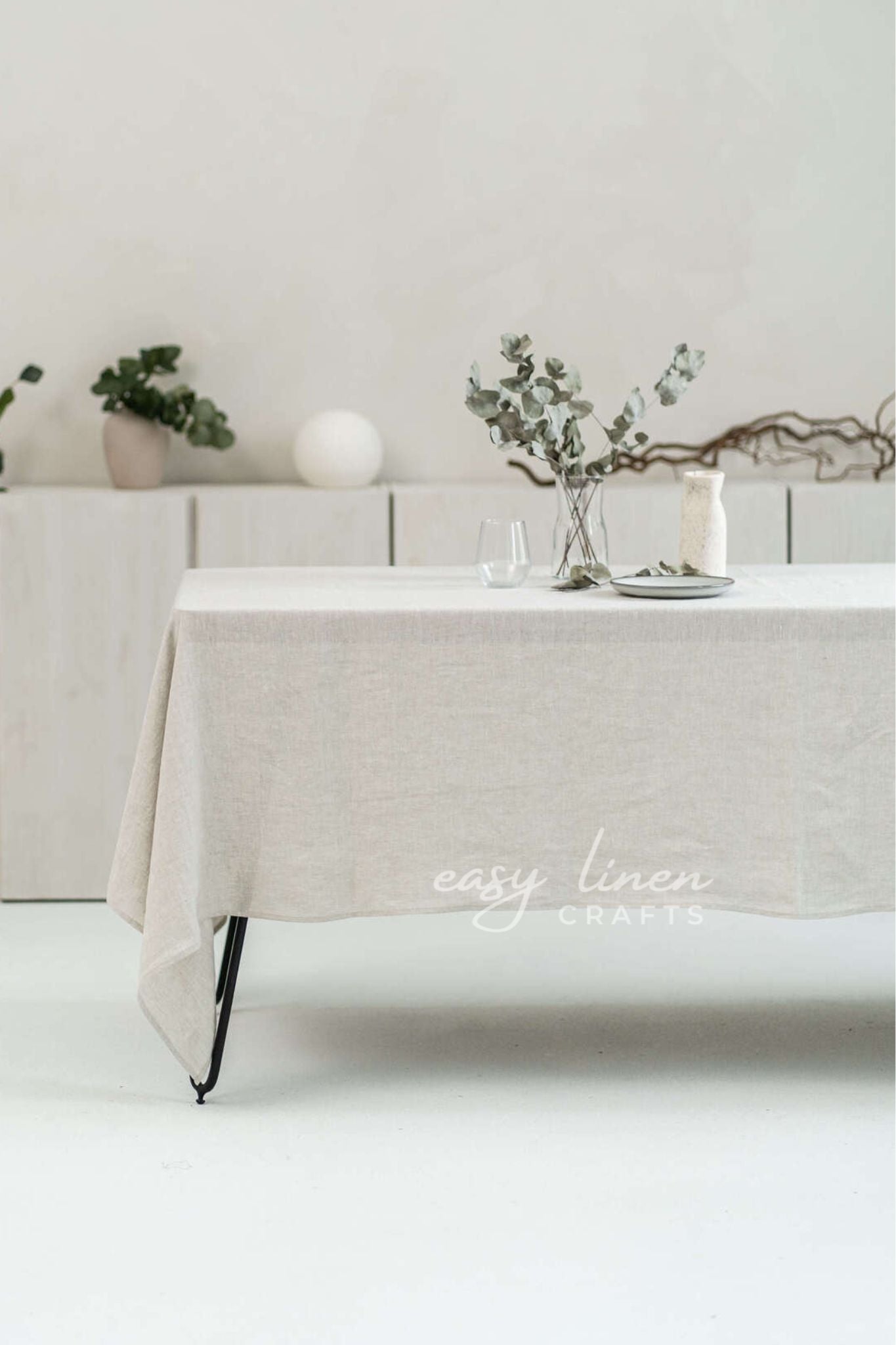 Beige linen tablecloth on a table with decorative elements in a minimalistic setting.