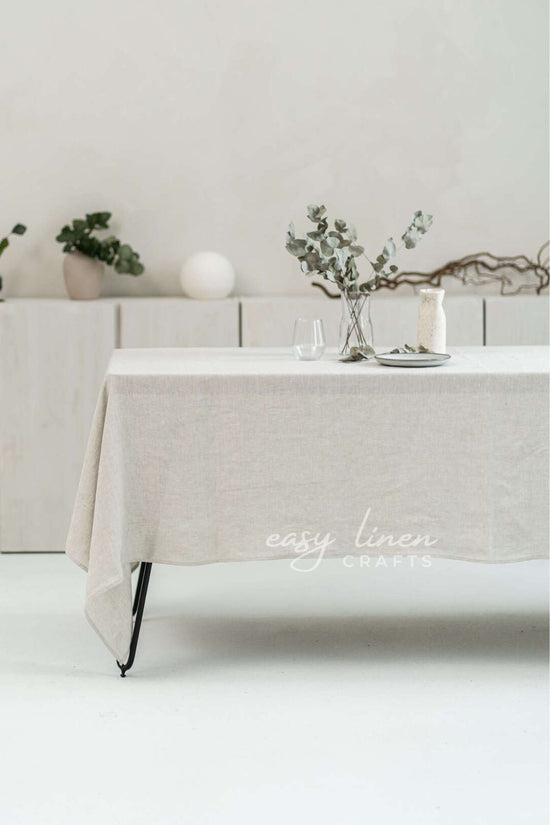 Beige linen tablecloth on a table with decorative elements in a minimalistic setting.