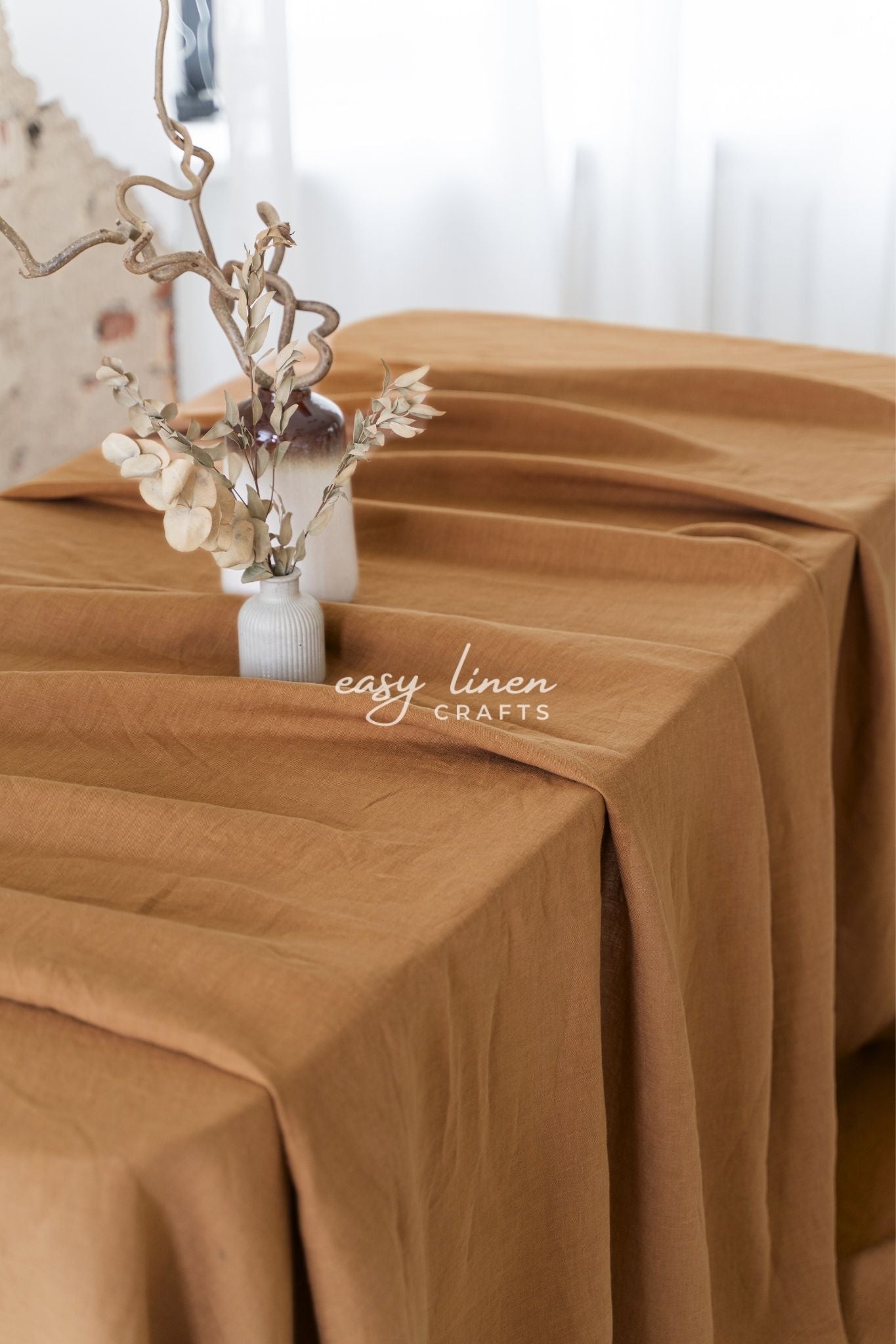 Brown tablecloth with a decorative vase and branches on a table, featuring 'easy linen crafts' branding.