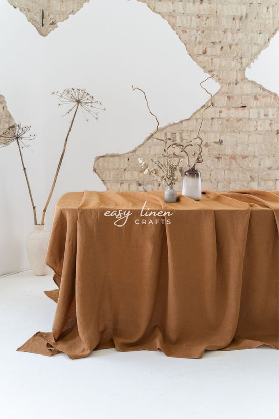 Brown tablecloth on a table with decorative elements against a textured wall.