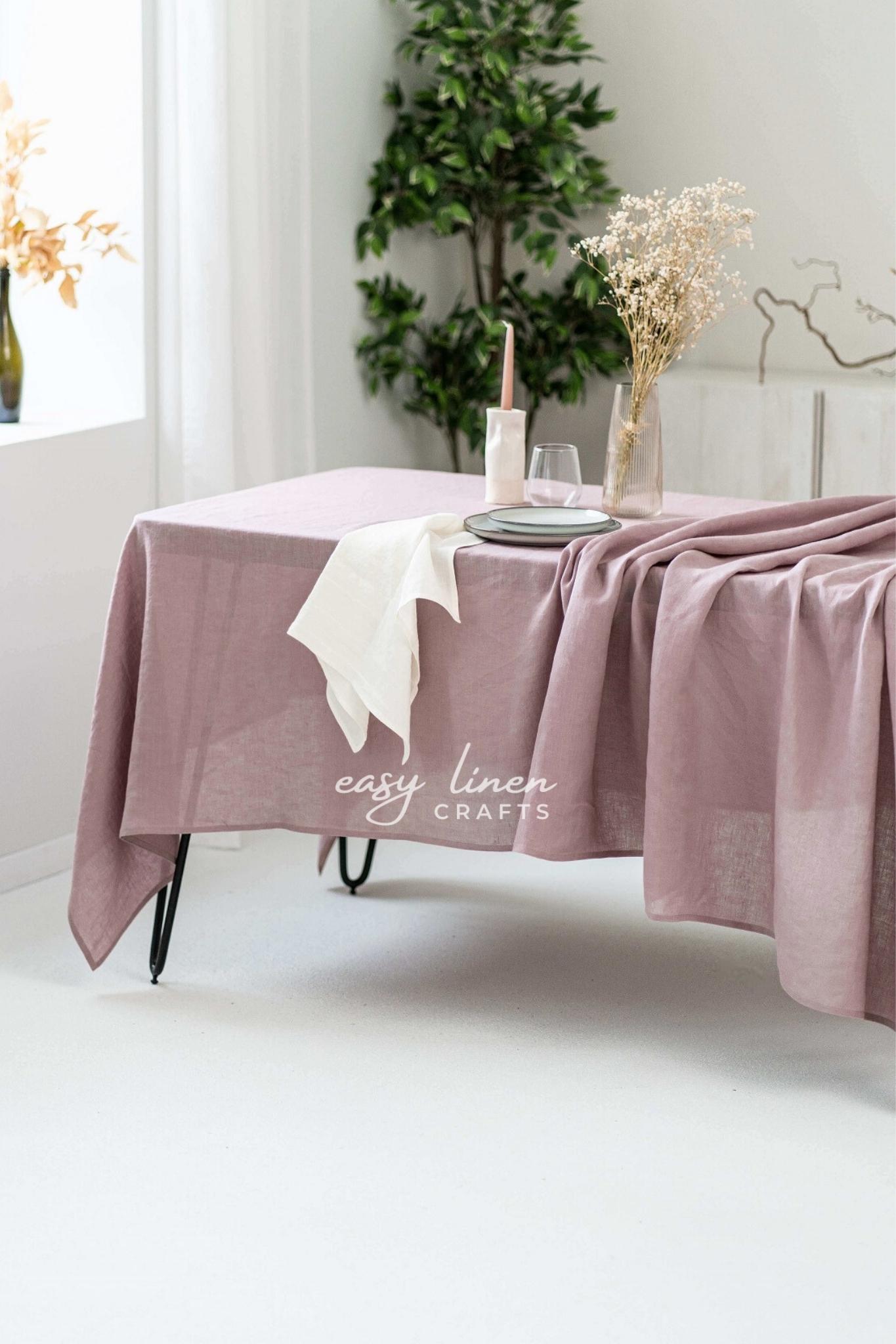 Dusty Rose linen tablecloth on a table with decorative elements in a bright room.