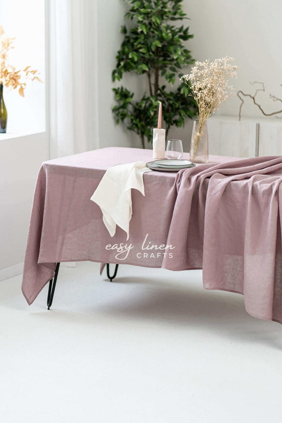 Dusty Rose linen tablecloth on a table with decorative elements in a bright room.