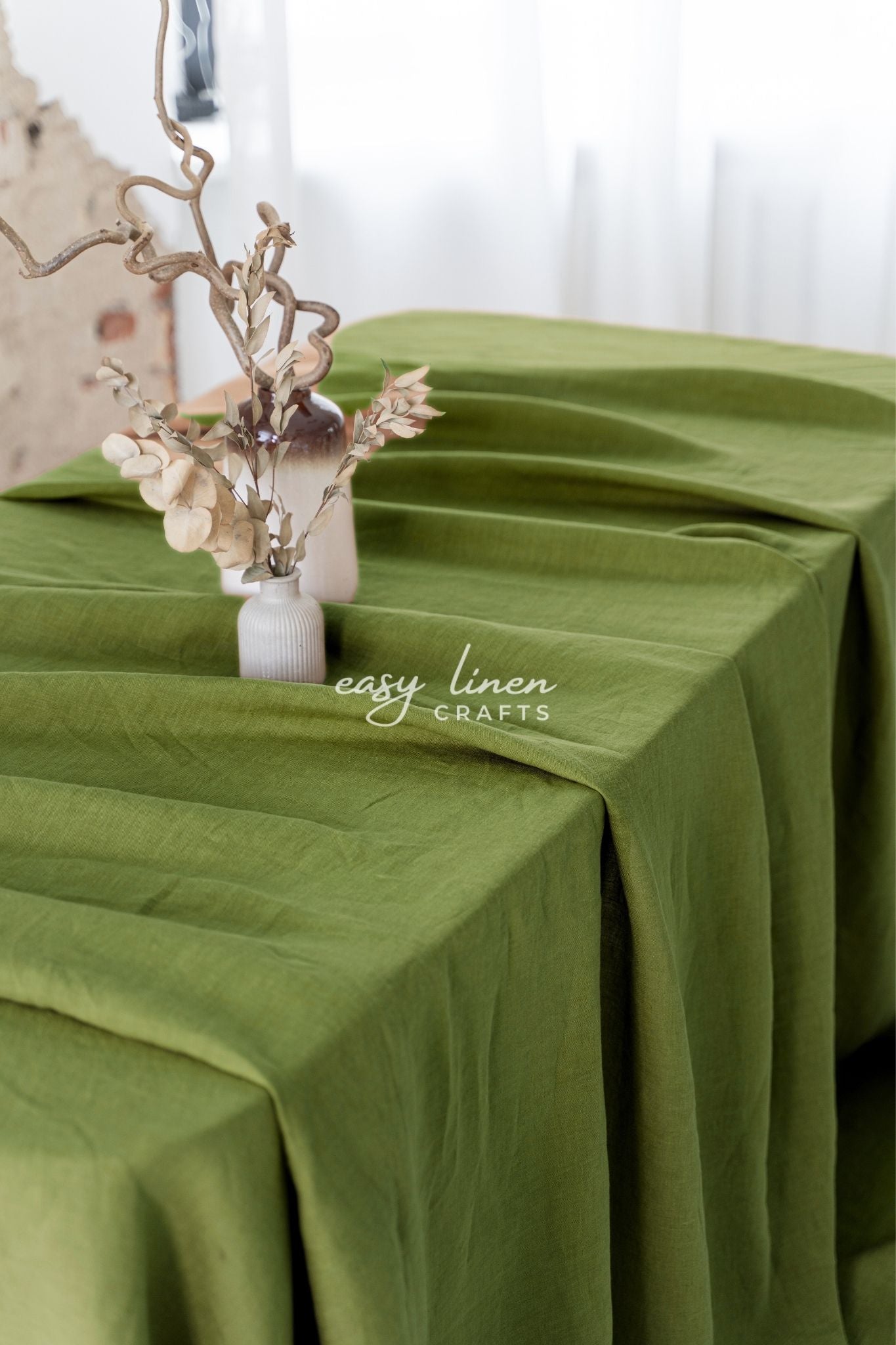 Green tablecloth with a decorative vase and branches on a white background, featuring 'easy linen crafts' branding.