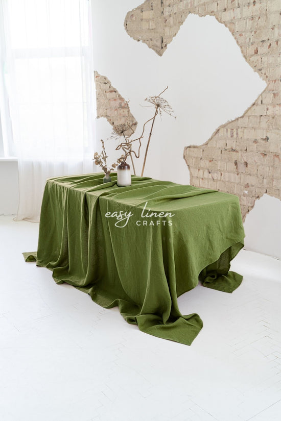 Green linen tablecloth on a table and textured wall background