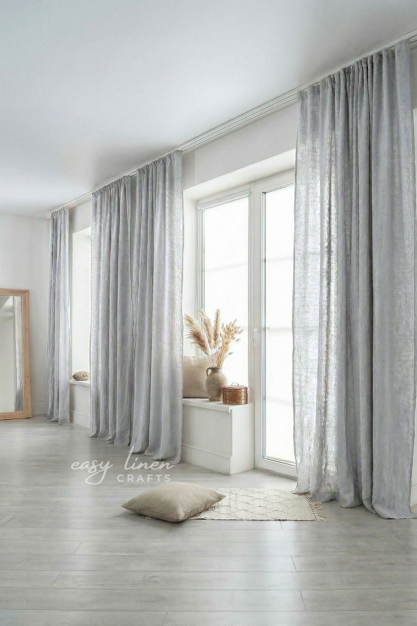 Light gray curtains in a room with a white floor and a window.