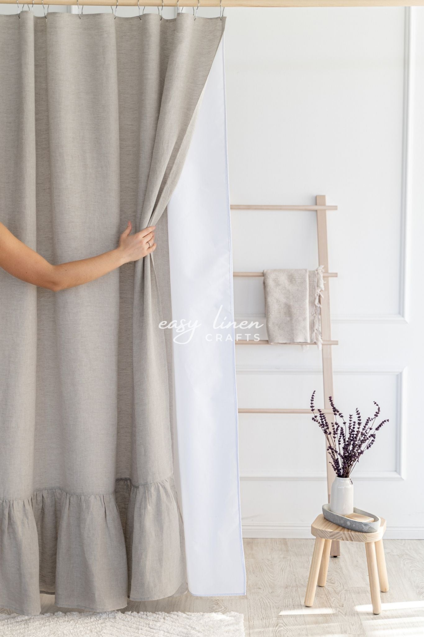 beige linen shower curtain in a room with a white wall and wooden stool.