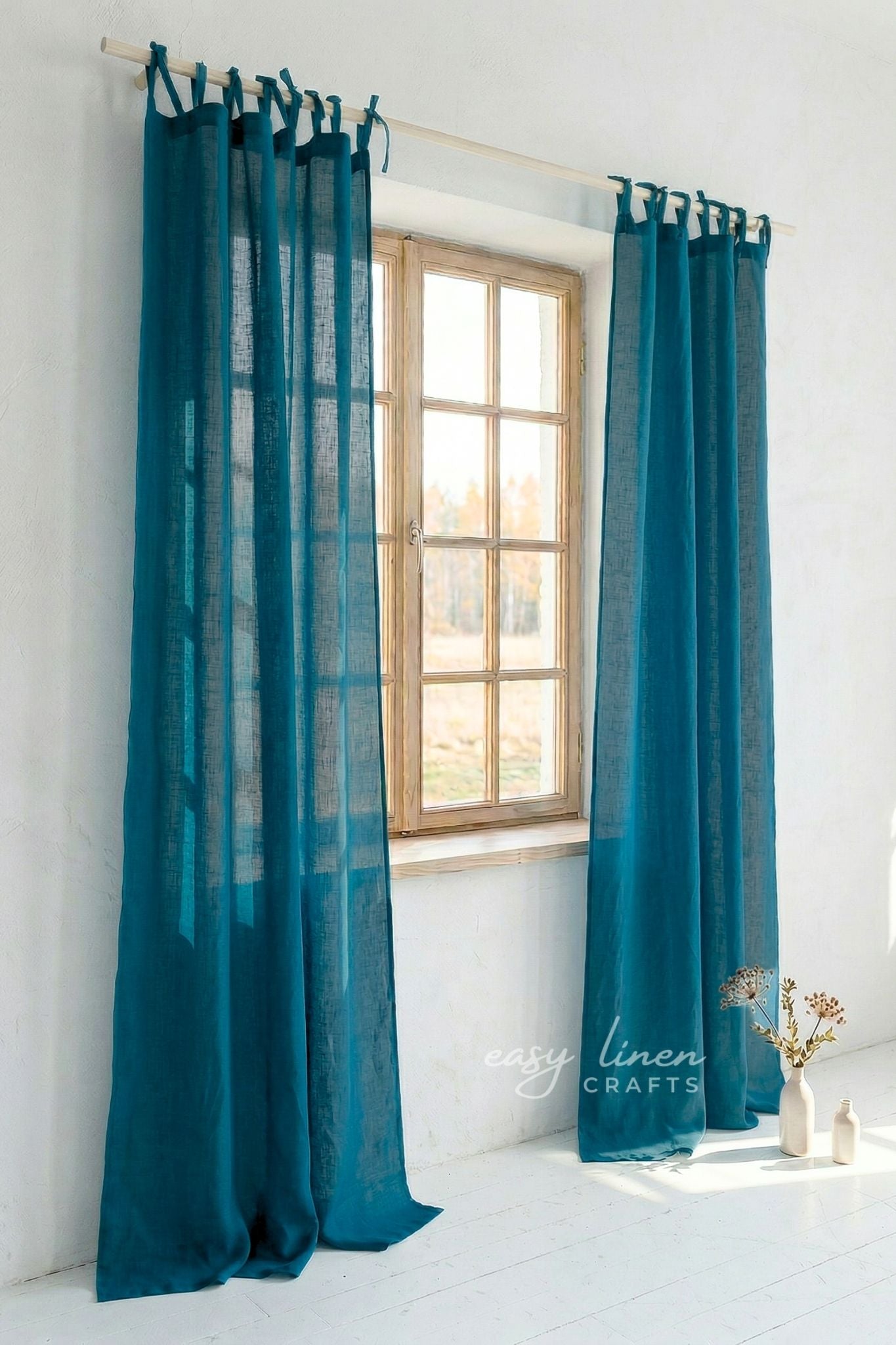 Teal curtains hanging in front of a window with a white wall background.