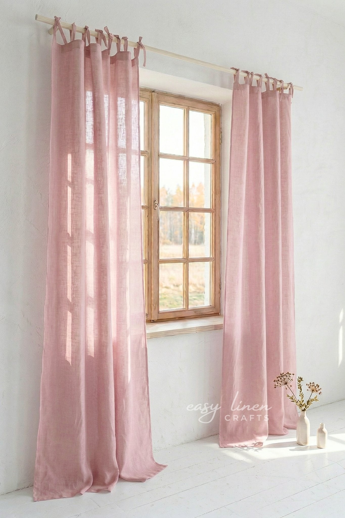Pink curtains hanging in a window with a light interior setting.