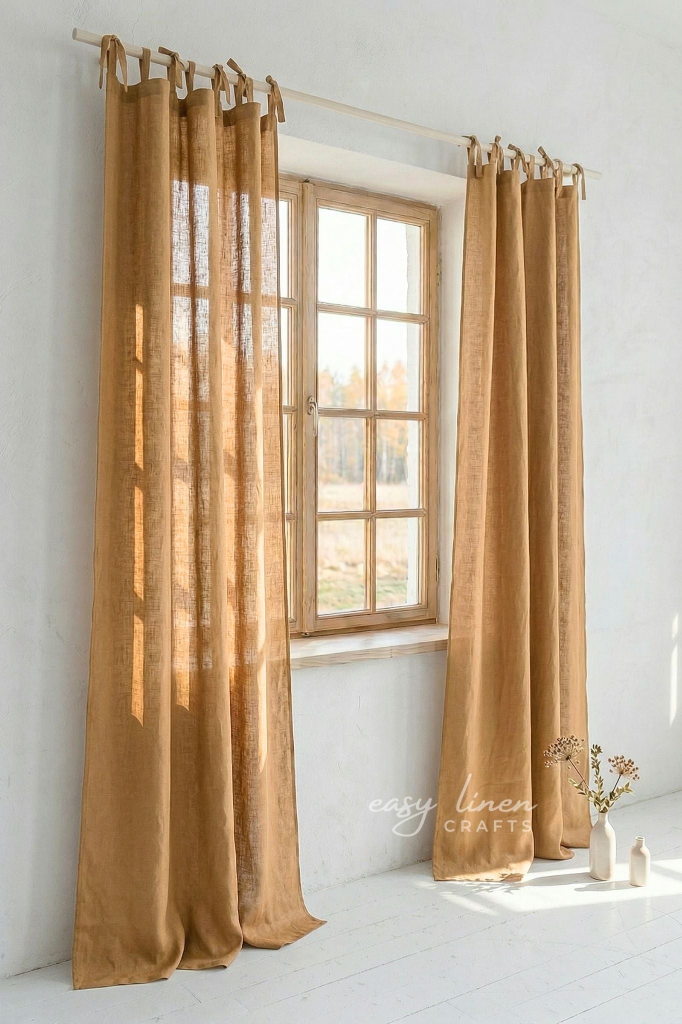 Gold curtains hanging in front of a window with a white wall background