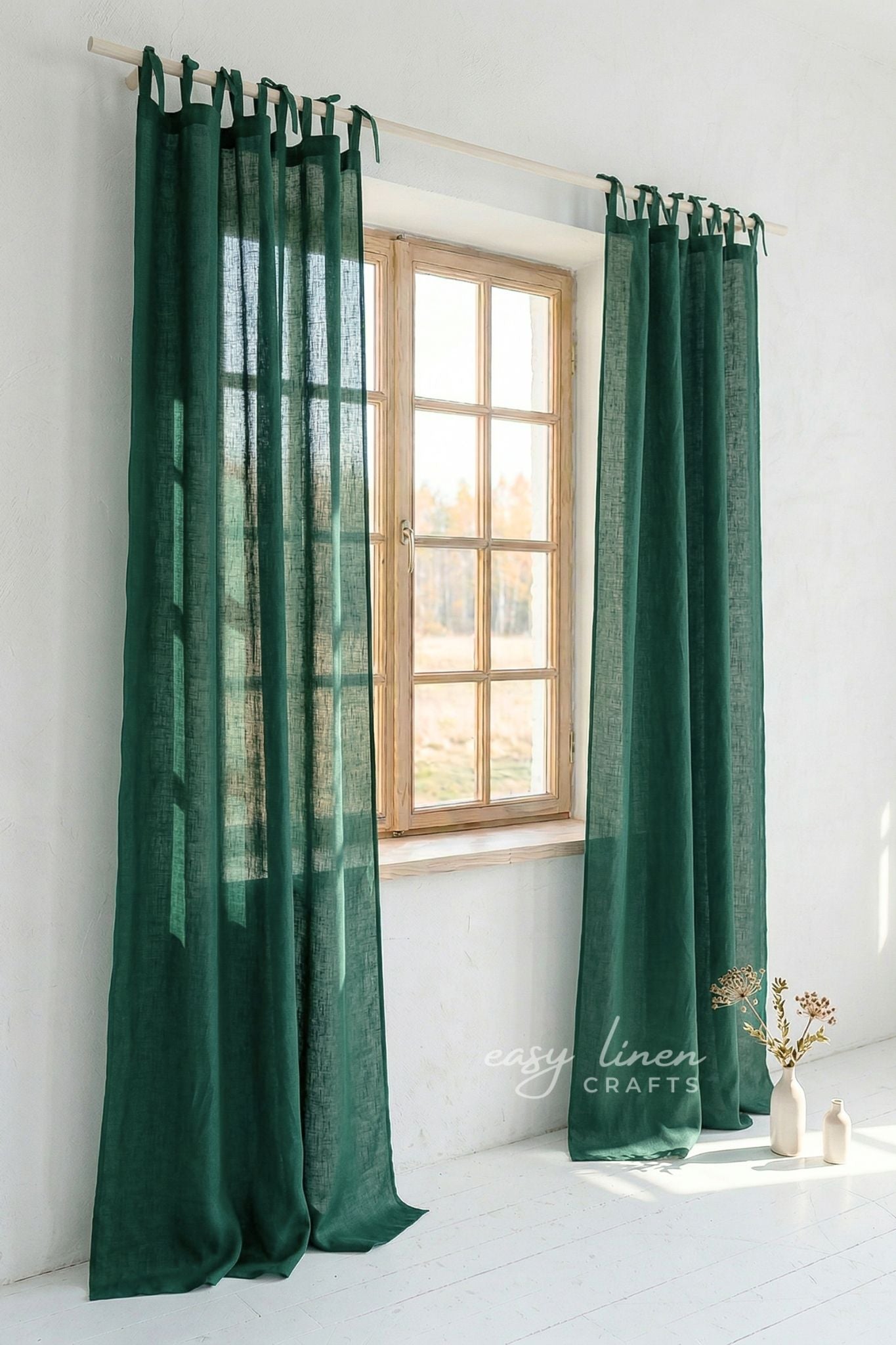 Green curtains hanging in front of a window with a white wall background