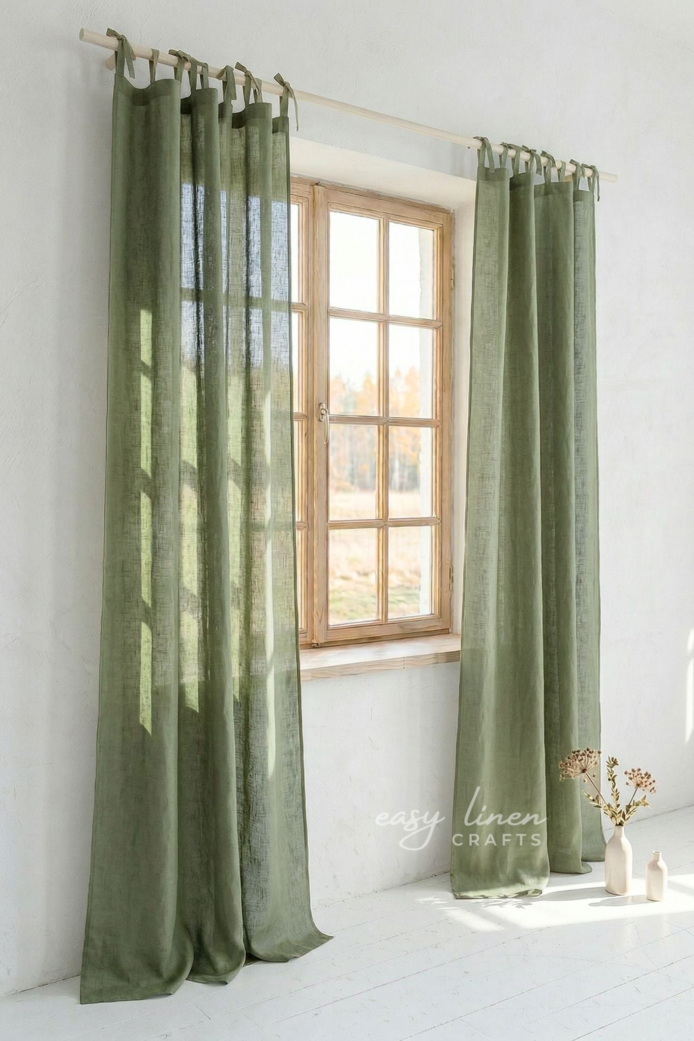 Khaki green linen curtain panels hanging on a wooden rod in a bright minimalist room