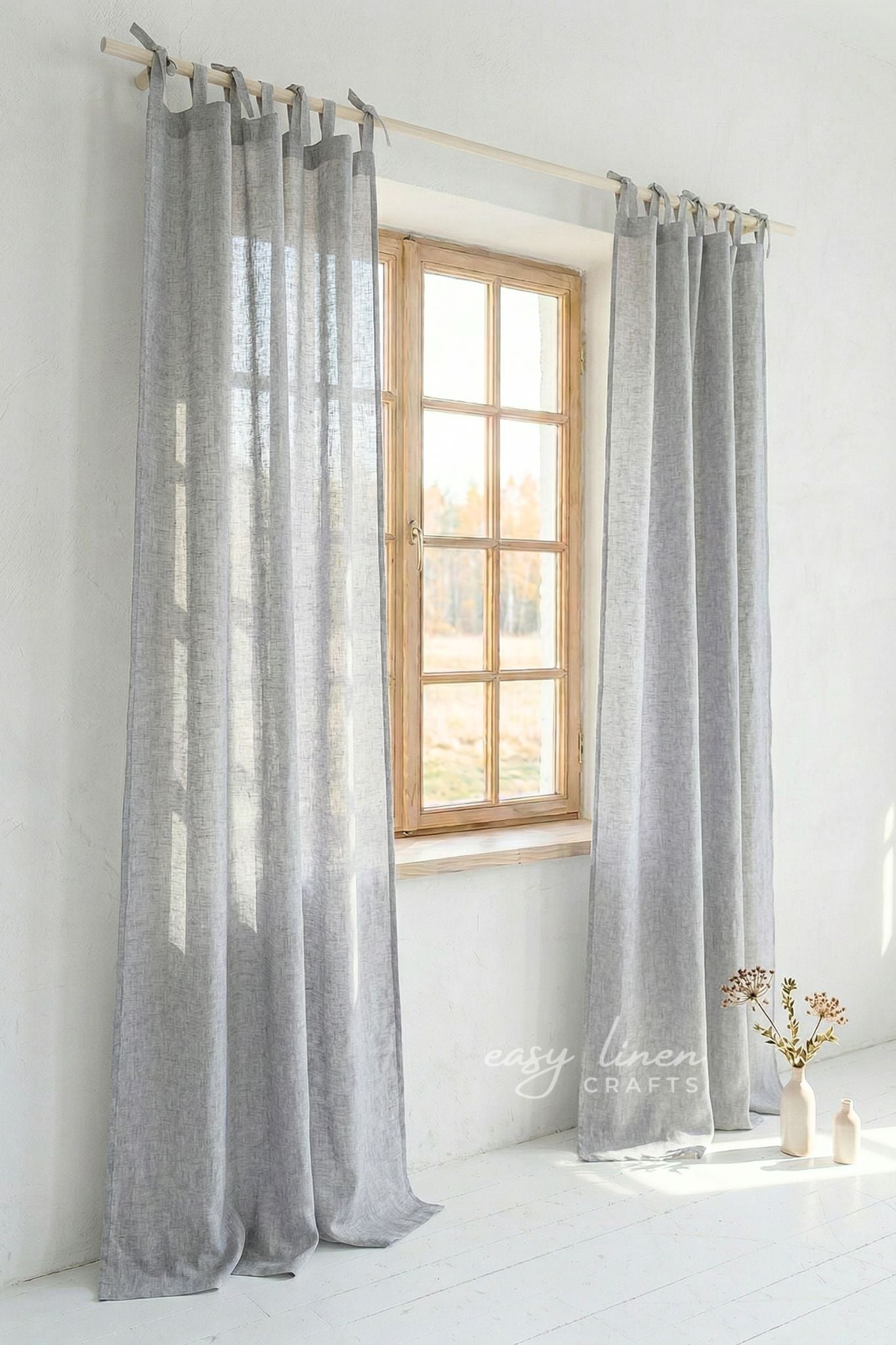 Gray curtains hanging in front of a window with a white wall background