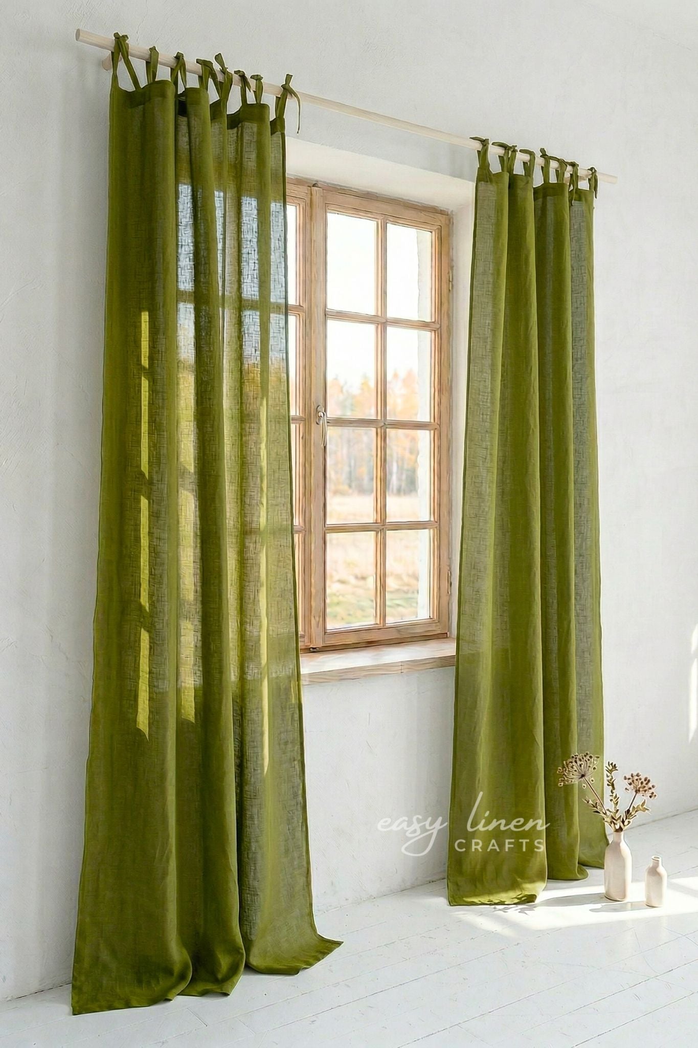 Green curtains hanging in front of a window with a white wall background