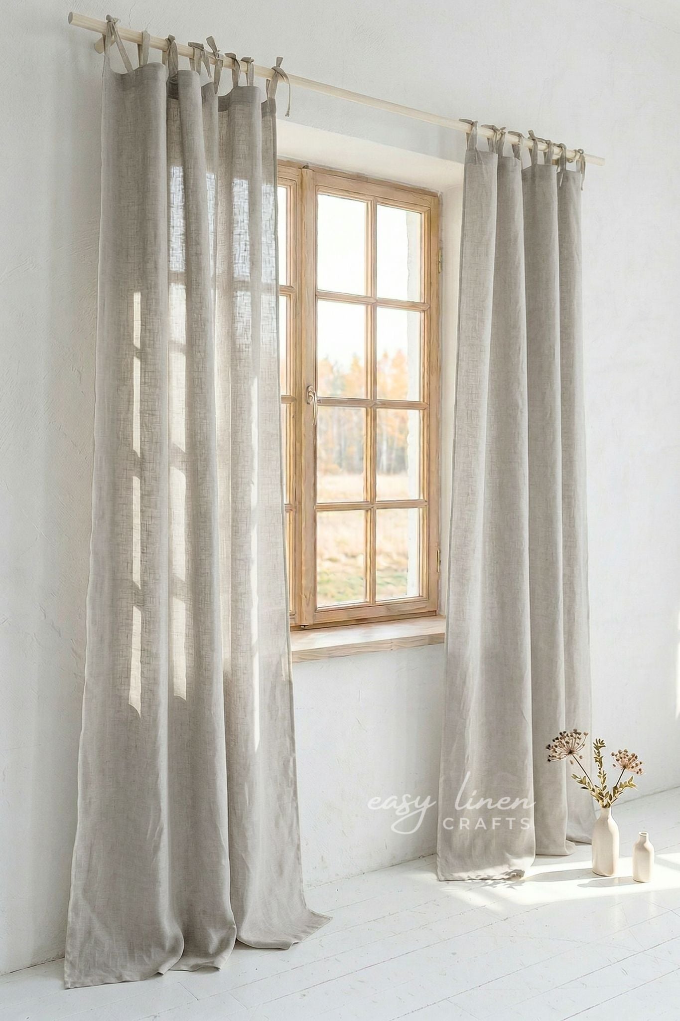 Natural curtains hanging in front of a window with a white wall background.
