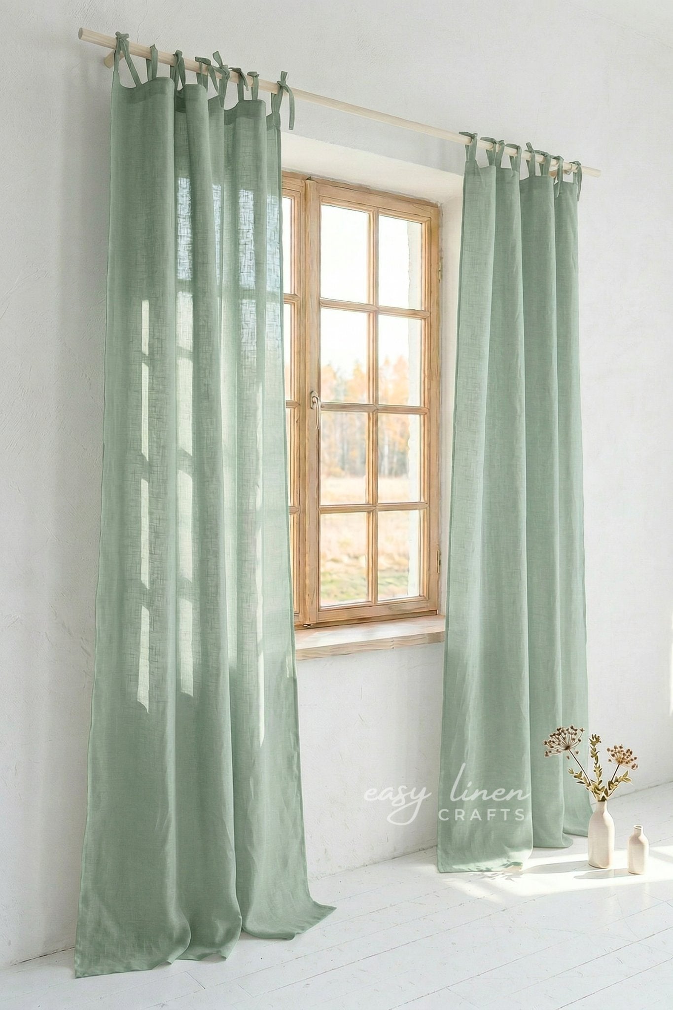 Green curtains hanging in front of a window with natural light.