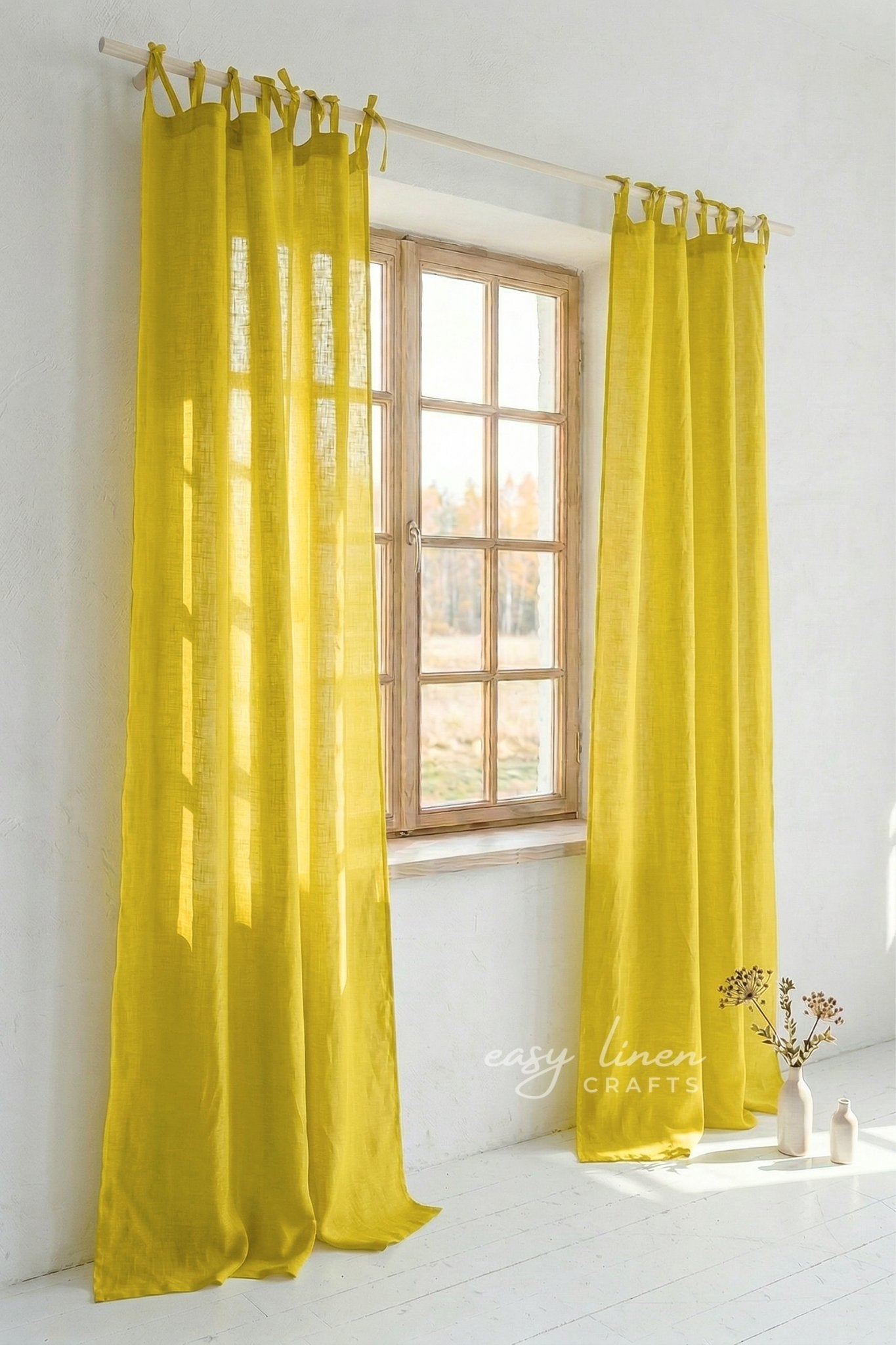 Yellow curtains hanging in a room with a window and decor.